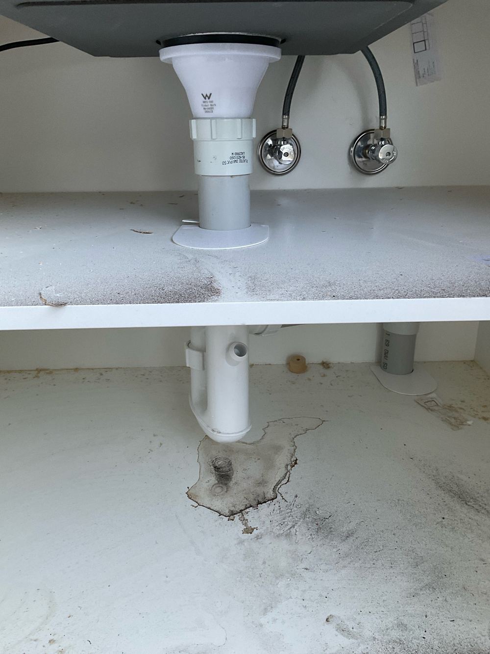 Leak under a basin, wetting the vanity floor, found during a pre-handover inspection in Werribee